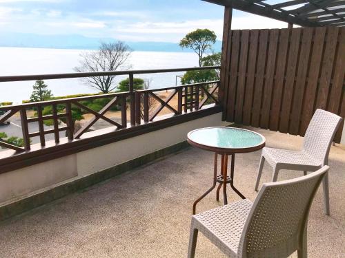 a balcony with two chairs and a table and a view of the water at Sennenmatsu in Imabari