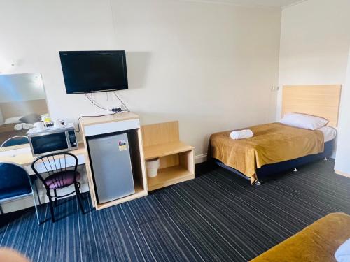 a small hotel room with a bed and a tv at Jacksons Motor Inn in Adelaide