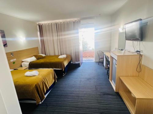a hotel room with two beds and a television at Jacksons Motor Inn in Adelaide
