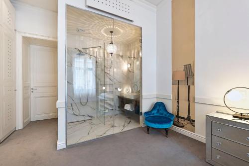 a dressing room with a blue chair and a glass wall at 6 Rooms in Vienna