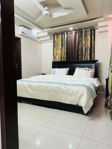 a bedroom with a large bed with white sheets and pillows at Com Heights Near Clock chowk bahria Town Lahore in Rāmkot