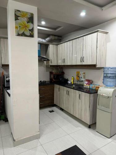 a kitchen with wooden cabinets and a white tile floor at Com Heights Near Clock chowk bahria Town Lahore in Rāmkot