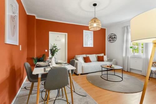 een woonkamer met oranje muren en een tafel en een bank bij Stilvolles Apartment mit Festungsblick im Zentrum in Königstein an der Elbe