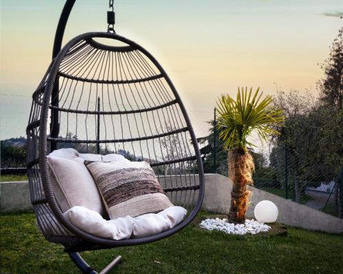 a hanging hammock chair in a yard with a palm tree at SalvatoreHomes - Luxury Villa with private Garden & BBQ in San Zeno di Montagna
