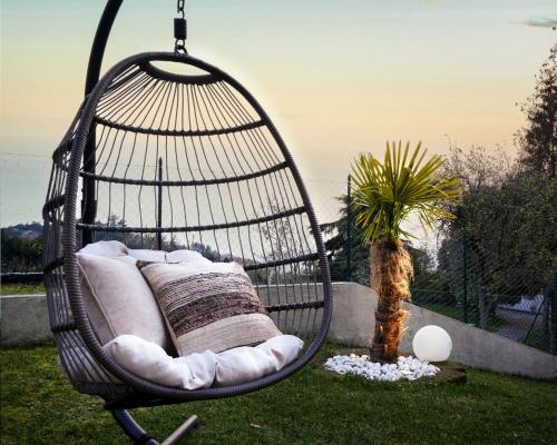 a hanging hammock chair in a yard with a palm tree at SalvatoreHomes - Luxury Villa with private Dream Garden & BBQ - Casa Palma - a 5 Star Luxury Collection at Lake Garda in San Zeno di Montagna