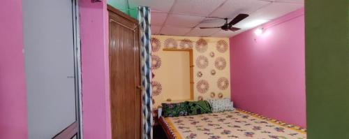 a room with pink and green walls and a couch at Anirudha Guest House in Digha