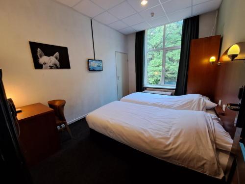 a hotel room with two beds and a window at Conferentiecentrum Hotel Bovendonk in Hoeven