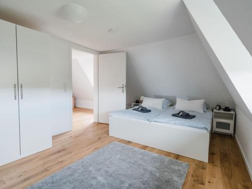 a white bedroom with a bed and a rug at Torbogenhuus No 5 in Norderney