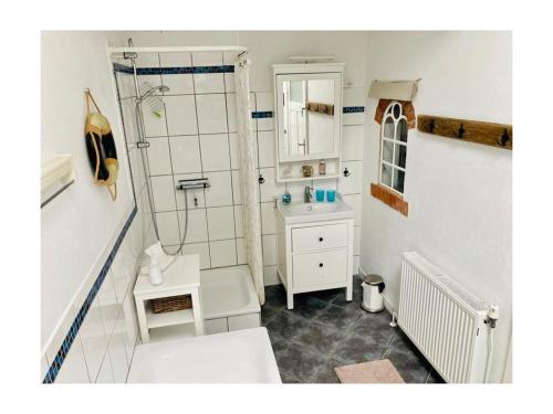 a white bathroom with a shower and a sink at Holiday apartment Nordnest in Dornum