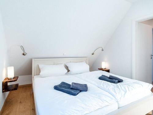 Una cama blanca con dos almohadas azules. en Nitschke - FeWo Flood, en Tannenhausen
