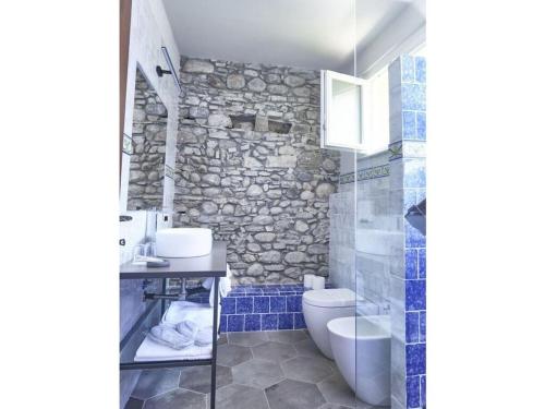 een badkamer met een toilet en een stenen muur bij Via Roma 53 - Bedero in Brezzo
