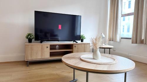 sala de estar con TV de pantalla plana en un centro de entretenimiento en City Centre Apartment by Noire Property, en Mánchester