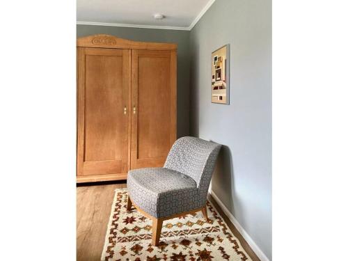 a chair sitting on a rug next to a cabinet at Bustards Modern retreat in Birresborn