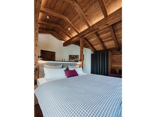 a large bed in a room with wooden ceilings at Chalet Alpin Modern retreat in Bayrischzell