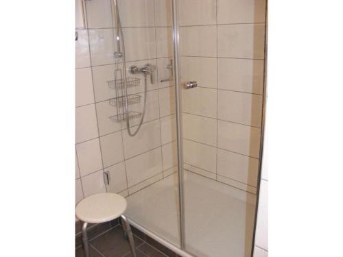 a shower with a glass door next to a stool at "Gänseliesel" Modern retreat in Willingen