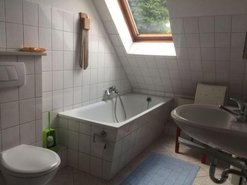 La salle de bains est pourvue d'une baignoire, d'un lavabo et de toilettes. dans l'établissement Heidehof Bunge Modern retreat, à Uelzen