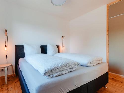 Una cama con sábanas blancas y almohadas. en Granetal Quartier-Apartment Wildblume en Goslar