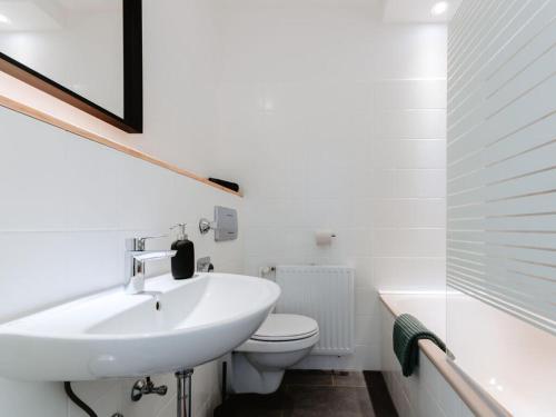 Baño blanco con lavabo y aseo en Granetal Quartier-Apartment Wildblume en Goslar