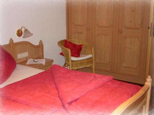ein Schlafzimmer mit einem Bett und einem Stuhl mit einer roten Decke in der Unterkunft Bader Modern retreat in Blaichach