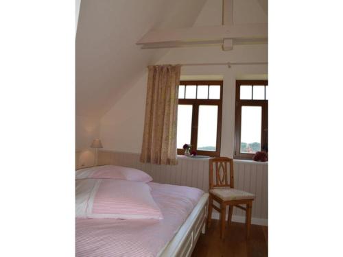 Schlafzimmer mit einem Bett, einem Stuhl und Fenstern in der Unterkunft Villa Taubenberg in Rinteln