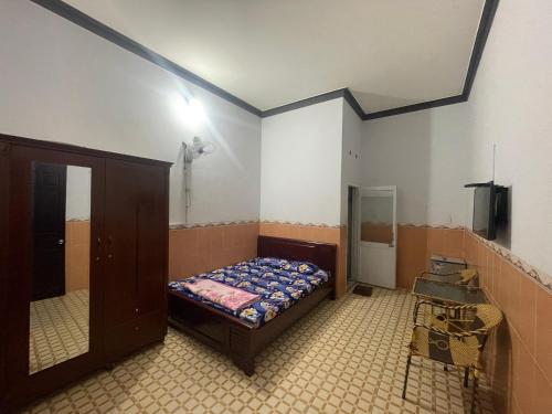 een slaapkamer met een bed en een spiegel bij Nhà nghỉ Trà My in Ấp Lò Vôi