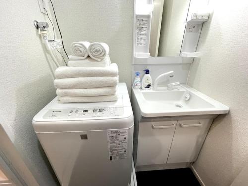 a bathroom with a toilet and a sink and towels at Nishi-Ike Apartment Room 1 in Tokyo