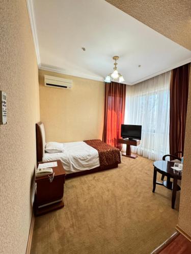 a hotel room with a bed and a television at Luxurious in Taraz