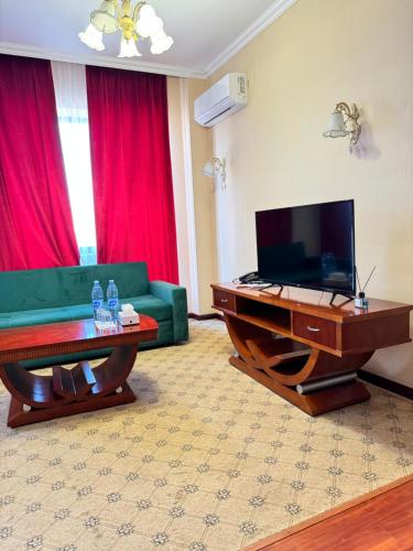 a living room with a green couch and a television at Luxurious in Taraz