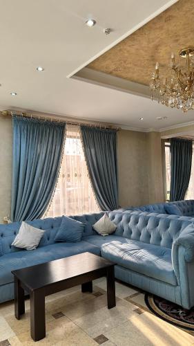 een grote blauwe bank in een kamer met blauwe gordijnen bij Luxurious in Taraz