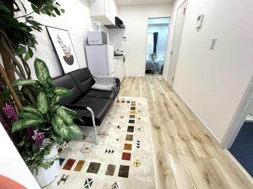 a living room with a black couch and some plants at Nishi-Ike Apartment Room 1 in Tokyo