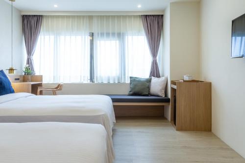a hotel room with two beds and a window at Hotel Ever Spring - Penghu in Magong