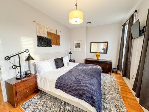 a bedroom with a bed and a table and a lamp at Renovated,steps To T,longwood Med in Brookline