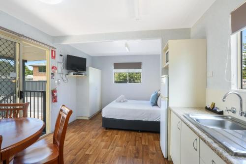 a room with a bed and a kitchen with a table at Reflections Tuncurry - Holiday Park in Tuncurry