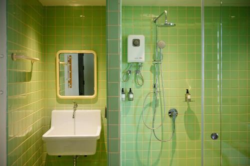 a green tiled bathroom with a shower and a sink at Stupid Stay in Bangkok
