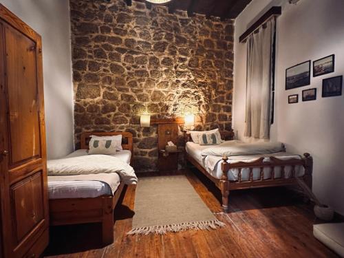Pokój z 2 łóżkami i kamienną ścianą w obiekcie El Quseir Hotel w mieście Al-Kusajr
