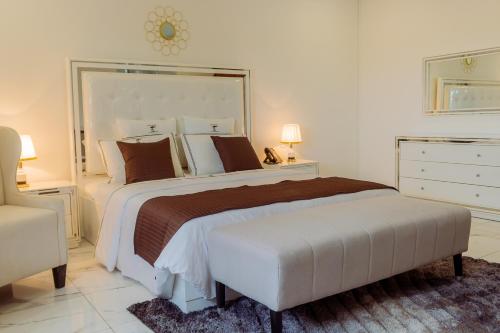 Hotel Estoril في بيرا: غرفة نوم بيضاء بسرير كبير وكرسي