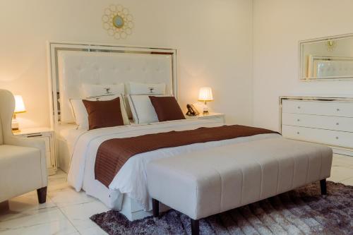 a white bedroom with a large bed and a chair at Hotel Estoril in Beira