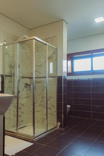 Hotel Estoril في بيرا: حمام مع دش زجاجي ومرحاض