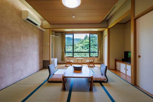 ein Wohnzimmer mit einem Tisch, Stühlen und einem Fenster in der Unterkunft Okutamaji in Ome