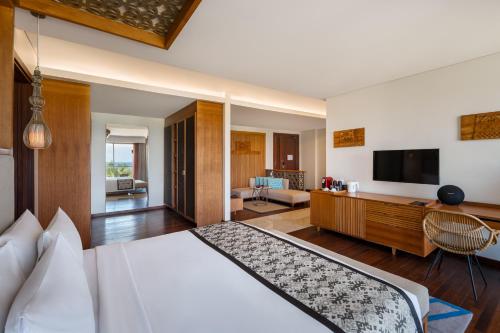 a hotel room with a bed and a television at MERUSAKA Nusa Dua in Nusa Dua