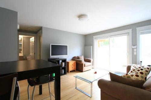a living room with a table and a couch and a television at QE Park Garden suite 3BR 1.5Ba in Vancouver