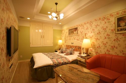 a bedroom with a bed and a couch and a chair at D-CUBE奈良店 in Nara