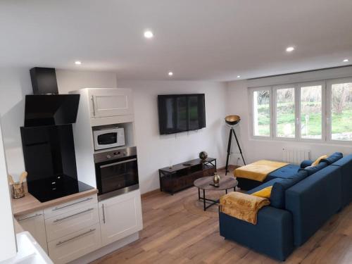 un salon avec un canapé bleu et une cuisine dans l'établissement Maison Villa Les chevaliers du Mont, à Argouges