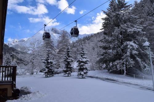 a ski lift in the snow with snow covered trees at Hotel Garni Pegrà in Ponte di Legno