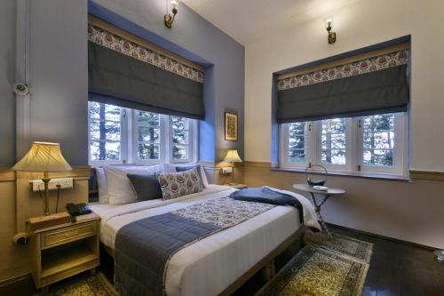 a bedroom with a large bed and two windows at Brij Villa, Dalhousie - A Colonial Luxury Retreat in Dalhousie
