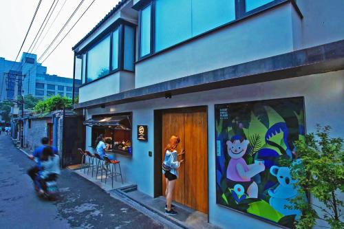 a woman standing outside of a building with a painting on it at 北京重构空间酒店天安门王府井店 in Beijing