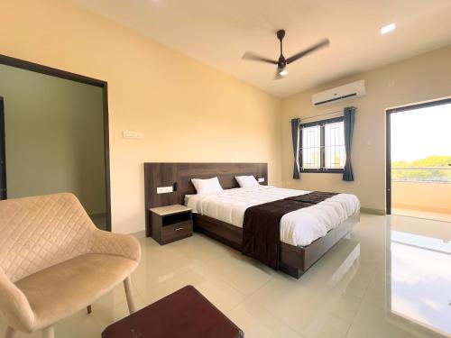 ein Schlafzimmer mit einem Bett, einem Stuhl und einem Fenster in der Unterkunft TULIP HOMES in Coimbatore