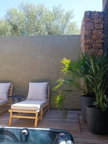 a patio with two chairs and a bath tub at Hôtel Les Suites Du Maquis in Bonifacio