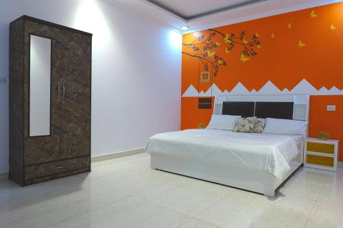 a bedroom with a bed with an orange wall at Embassy Suites in New Delhi