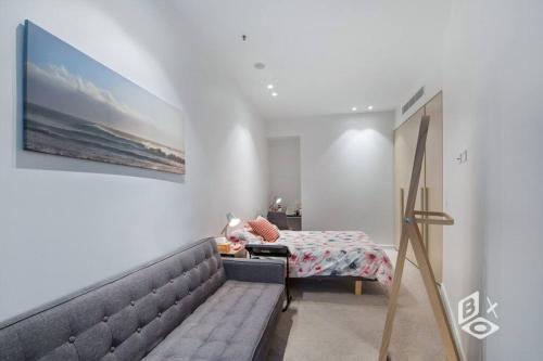 a bedroom with a couch and a bed and a painting at Rest 1 BedRooms Fawkner APT in Melbourne